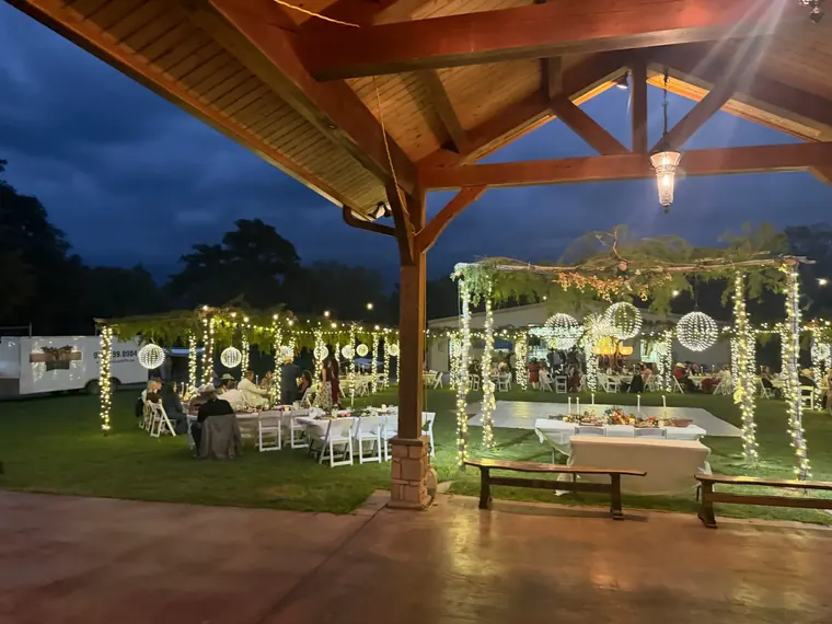 Pavilion at night seen from the lawn, with a lit arch and wrapped columns.