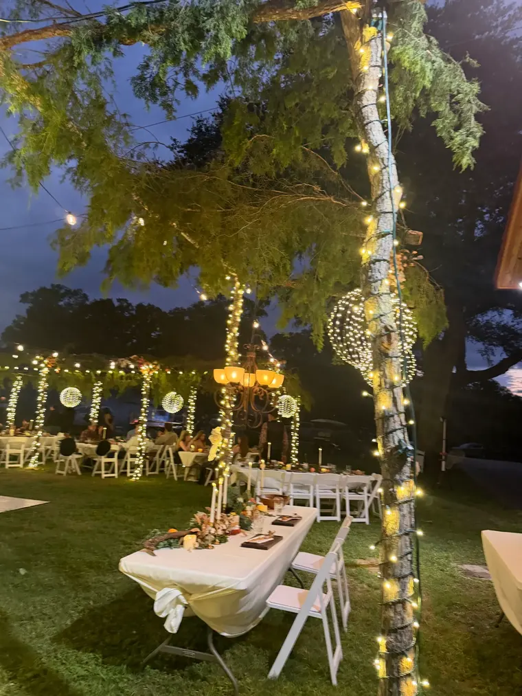 Table setting at night beneath wrapped branches and hanging light spheres.