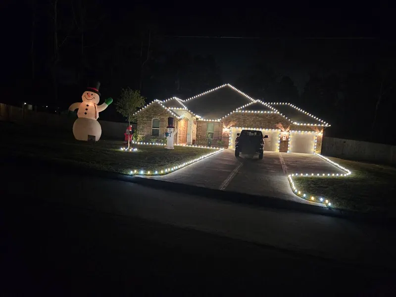 Brick ranch home on a dark street with warm-white rooflines, garage doors outlined and a driveway edged in C9 lights.